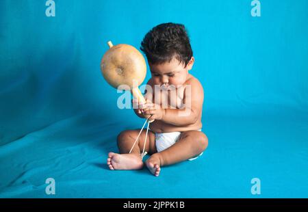 Native American baby, from the Santa Clara Pueblo shakes a traditional gourd rattle used for dances and ceremonies in New Mexico Stock Photo