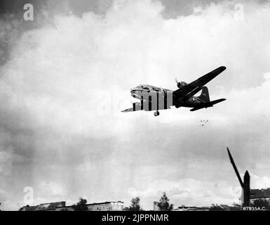 C-54 dropping candy during Berlin Airlift, circa 1949. A U.S. Air Force Douglas C-54 Skymaster making a 'Little Vittles' candy drop (note the parachutes below the tail of the C-54) on approach to a Berlin airfield. Aircrews dropped candy to children during the Berlin Airlift. Stock Photo