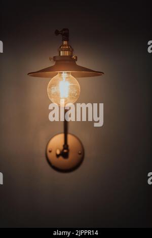 Old light bulb on a modern blue wall. Selective focus  Stock Photo