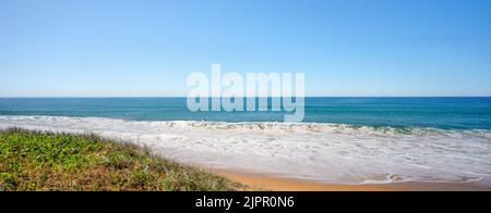 Foam from backwash from ocean waves breaking onto a sandy beach at Buddina, Queensland. Stock Photo