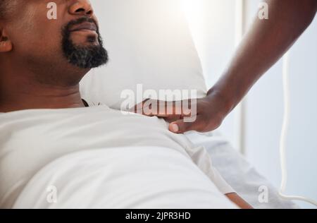 Sick, ICU or ill man lying on a hospital bed with support and care from a person inside. Closeup of an African American male patient getting medical Stock Photo