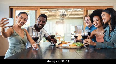 Diverse friends taking selfie on a phone while bonding, drinking wine and eating together at a restaurant. Fun group enjoying gathering, reunion Stock Photo