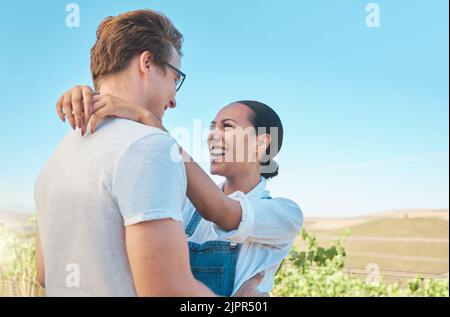 Laughing, in love and happy interracial couple in hug, embrace or holding each other on wine tasting farm. Fun, playful or loving man and woman Stock Photo