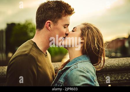 They are very much in love. a loving young couple sharing a kiss while out on a date. Stock Photo