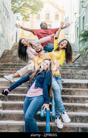 Group of happy diverse young friends having fun together at city streets with arms raised - Friendship concept Stock Photo