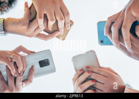 Close up shot of teenager group of people using their phones outdoors. Education, technology and happiness concept Stock Photo