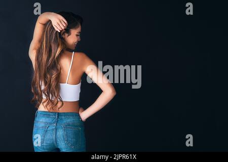 I just cant stop touching my voluminous, healthy hair. Studio shot of an attractive young woman posing against a dark background. Stock Photo