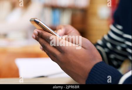 I never go anywhere without it. an unrecognizable student using his cellphone. Stock Photo