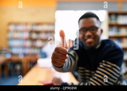 Feeling positive about my future. Cropped portrait of a student showing thumbs up while sitting in the library. Stock Photo