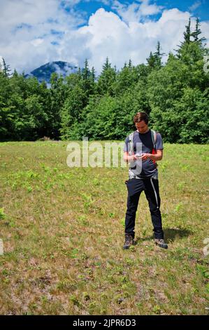 Mature man using mobile phone with GPS while hiking in mountains Stock Photo