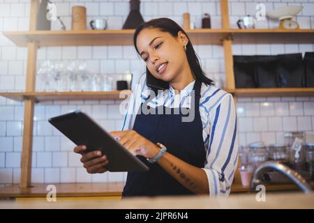 Cafe manager, planning online customer orders and working on digital tablet with internet, phone call and sales in restaurant startup. Small business Stock Photo