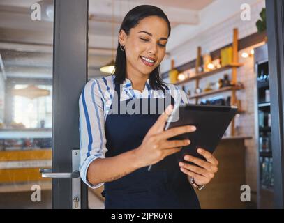 Startup, entrepreneur and female cafe owner working on a digital tablet to plan a budget. Proud, positive and successful leader checking inventory Stock Photo