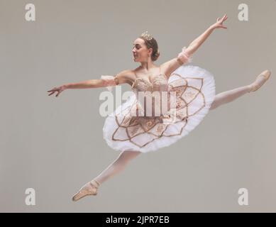 Jumping ballet dancer or ballerina performer dancing in a beautiful, elegant tutu dress or fashion design costume in studio performance. Talented Stock Photo