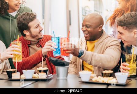 Happy multiracial friends group toast, drink and eating at restaurant meeting - Life style concept with hipster friends sharing happy hour time togeth Stock Photo