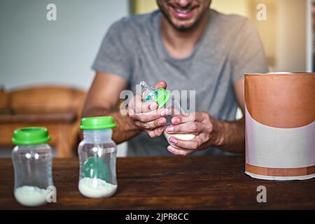 Preparing babys bottle. an unrecognizable single father preparing a bottle for his baby at home. Stock Photo