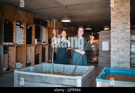 Wine making, production and cellar workers crush, blend and stir open tank for alcohol process. Portrait of happy staff in factory and winery industry Stock Photo