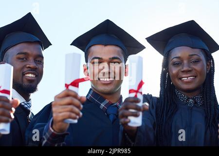 So happy we could share this big day together. Portrait of a group of students holding their diplomas on graduation day. Stock Photo