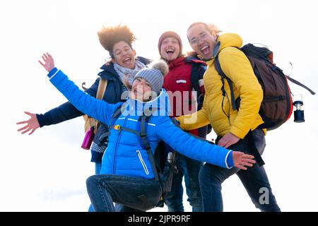 Cheerful group of hiker friends taking a selfie with arms in the air on top of the mountain - Hiking or trekking concept - white background Stock Photo