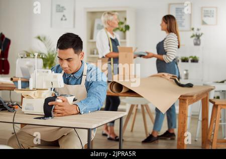 Tailor, seamstress and creative designer working on a sewing machine in a design studio or workshop. Fashion, style and creativity with a young man Stock Photo