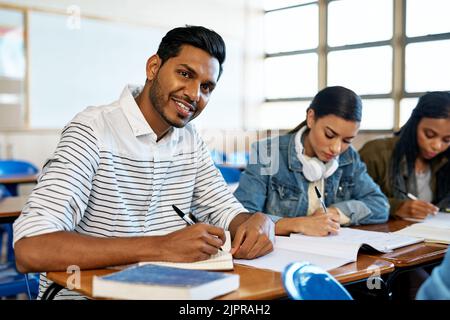 If I write it, I wont forget it. Cropped portrait of a handsome young university student taking notes while sitting in class. Stock Photo