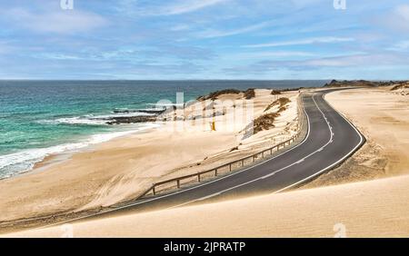 road passing through the dunes next to the beach in the dunes of Corralejo, Fuerteventura, Canary Islands, Spain Stock Photo