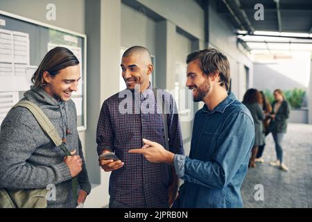 Navigating the college experience with smart apps. a group of young students using a mobile phone together on campus. Stock Photo