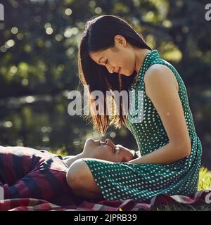 The perfect spot for some romance. an affectionate young couple relaxing together on a picnic blanket in the park. Stock Photo