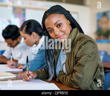 Im dedicated to my studies. Cropped portrait of an attractive young university student taking notes while sitting in class. Stock Photo
