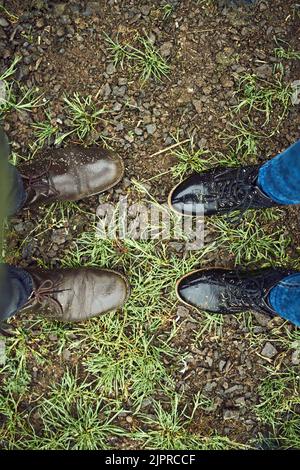 You have some big shoes to fill. two unrecognizable peoples shoes standing next to each other on a patch of grass outside during the day. Stock Photo