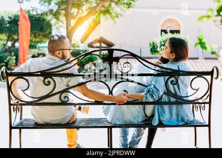 Rear view of unfaithful woman holding hands with another man while