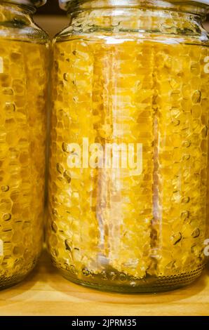 Honey and honeycomb in glass bottles packaged for sale. Stock Photo