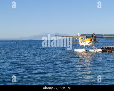 Taupo New Zealand - January 11 2002; Tourist float plane at pier refueling on on popular traveler attraction with mountains in distance across lake. Stock Photo