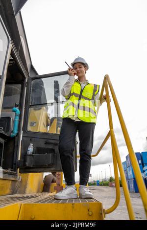 Female Foreman stay on lifting forklift container cargo forklift using walkie talkie for communication and control forklift concept service transporta Stock Photo