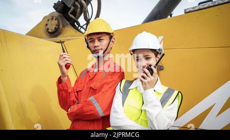 Woman Manager and foreman using walkie talkie at side of Cargo forklift in warehouse , Manager use tablet in white helmet Safety Supervisor in Contain Stock Photo