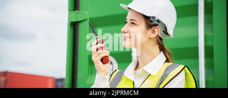Female Foreman stay in front of container cargo using walkie talkie for communication and control forklift concept service transportation logistic. Sa Stock Photo
