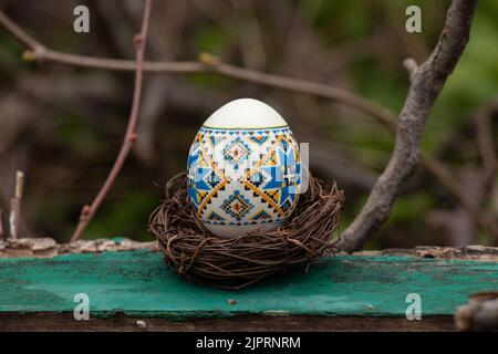 Painted chicken egg in a straw basket on tree branches in Ukraine, Easter holiday during the war in Ukraine 2022 Stock Photo