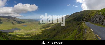 panorama landscape with the steep and winding mountain road leading to the top of Connor Pass on the Dingle Peninsula in County Kerry Stock Photo