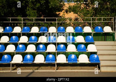 Empty blue and white plastic seats on stands of stadium in open. Concept of sport lifestyle. Stock Photo