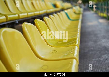 Empty yellow and green plastic seats on stands of stadium in open. Concept of sport lifestyle. Stock Photo