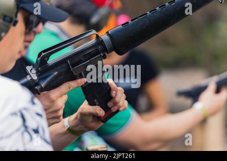 2022.08.07 Modlin, Poland - Group of people training how to operate guns. Firearm training at firing range. Safety gear. Close-up of submachine gun. Outdoor horizontal shot . High quality photo Stock Photo