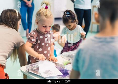 preschoolers using creative painting techniques for their painting at nursery, Ebru art. High quality photo Stock Photo
