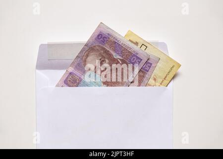 Ukrainian 50 and 100 UAH lie in a white envelope on a white background, financial background, hryvnia Ukraine Stock Photo