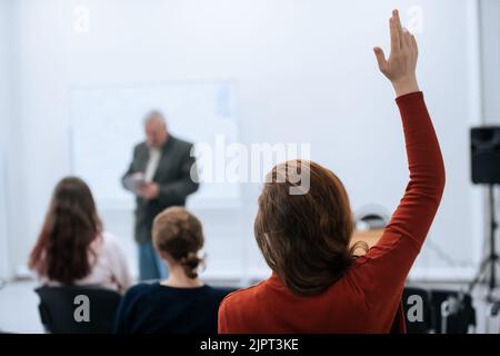 A famous professor has arrived at the university to conduct a special lesson, the student pulls his hand up to ask him a question. Stock Photo