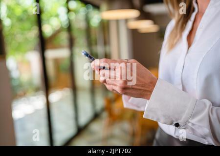 midsection of hands of unknown woman caucasian female standing at home wear white waist up copy space side view portrait using mobile phone for textin Stock Photo