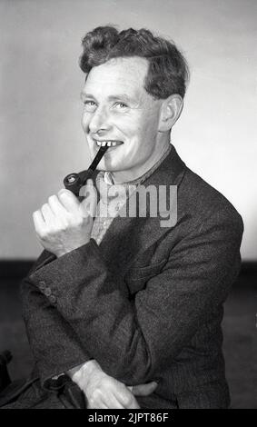 1950s, historical, happy pipe smoker, potrtrait of a youngest man, mid-30s; wearing a sweater and sports jacket sitting for his phtoto, enjoying his pipe, England, UK. Stock Photo