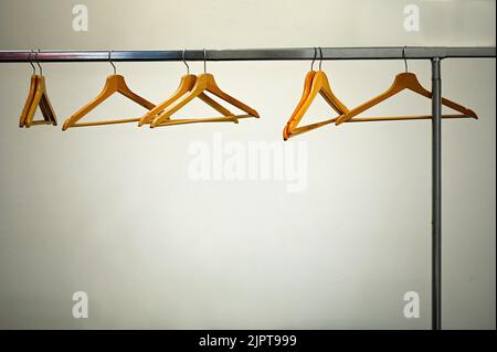 A deserted cloakroom view with clothes rack and wooden hangers on white wall Stock Photo