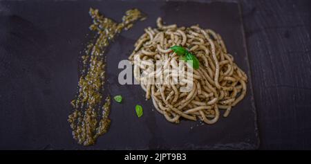 Pasta with pesto sauce on dark background, top view Stock Photo