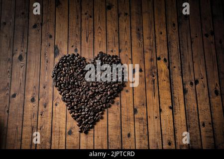 The Heart shape made from coffee beans on wooden surface. Stock Photo
