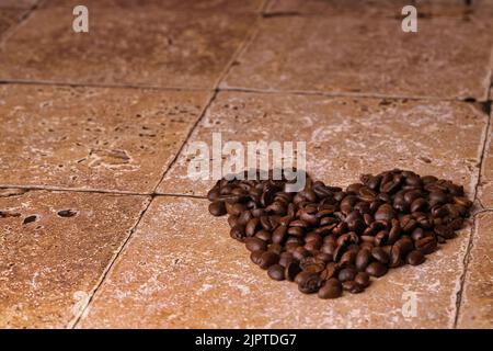 The Heart shape made from coffee beans on stone surface. Stock Photo