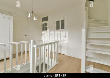 Interior of narrow corridor with telephone and radiator hanging on wall against stairway in daylight Stock Photo